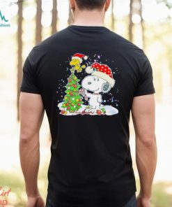 Snoopy and Woodstock wear Santa hats by the pine tree Christmas shirt