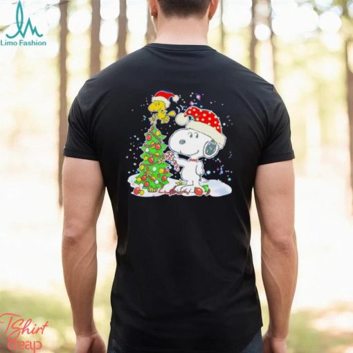 Snoopy and Woodstock wear Santa hats by the pine tree Christmas shirt