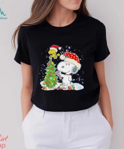 Snoopy and Woodstock wear Santa hats by the pine tree Christmas shirt