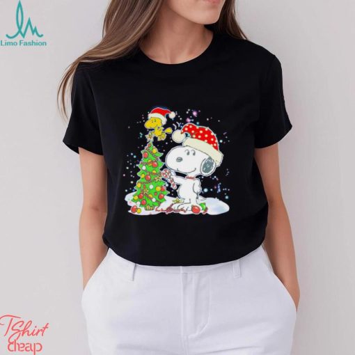 Snoopy and Woodstock wear Santa hats by the pine tree Christmas shirt