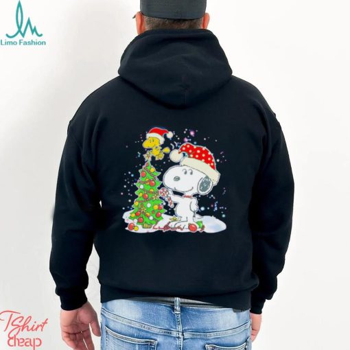 Snoopy and Woodstock wear Santa hats by the pine tree Christmas shirt