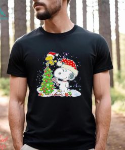 Snoopy and Woodstock wear Santa hats by the pine tree Christmas shirt