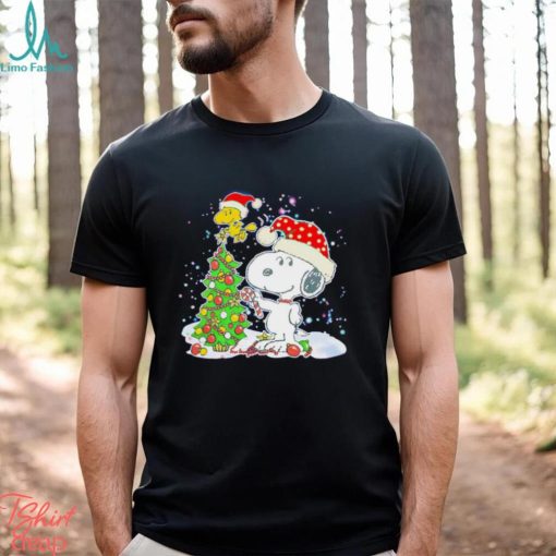 Snoopy and Woodstock wear Santa hats by the pine tree Christmas shirt